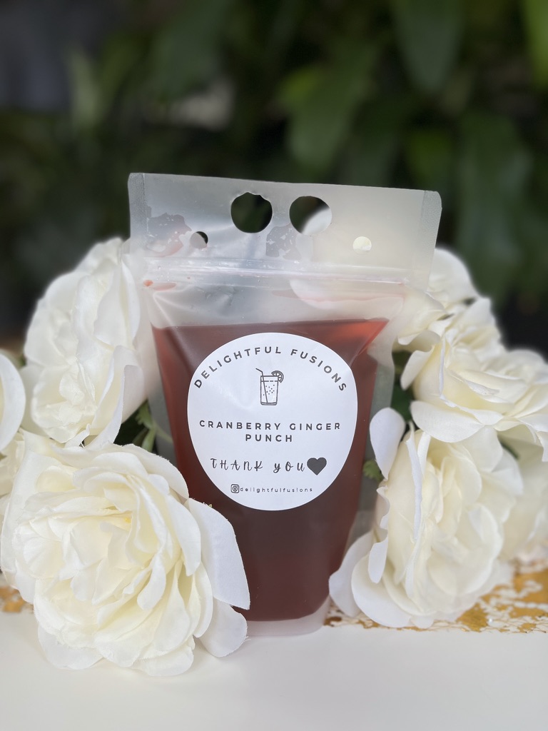 A Cranberry Ginger Punch pouch nestled among white roses